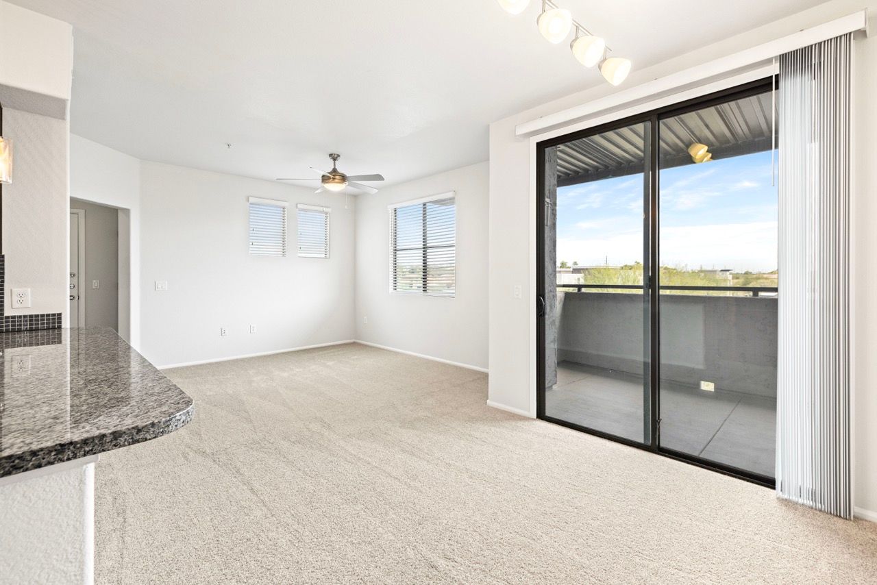 Interior living area with carpet, granite kitchen counter, and sliding glass door to balcony.