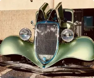 Green vintage car with open hood, parked in front of a building. | Arizona Engine Rebuilding