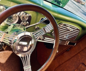 Chrome steering wheel and dashboard in a vintage green car with brown interior. | Arizona Engine Rebuilding