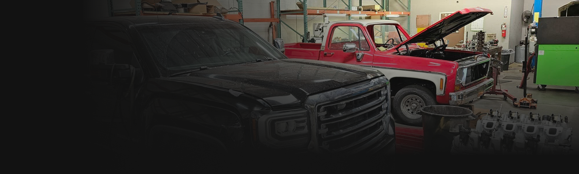 Black pickup truck next to a red truck with open hood in a garage. | Arizona Engine Rebuilding