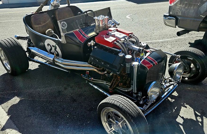 Hot rod car with exposed engine, black body, number 23, parked on asphalt. | Arizona Engine Rebuilding