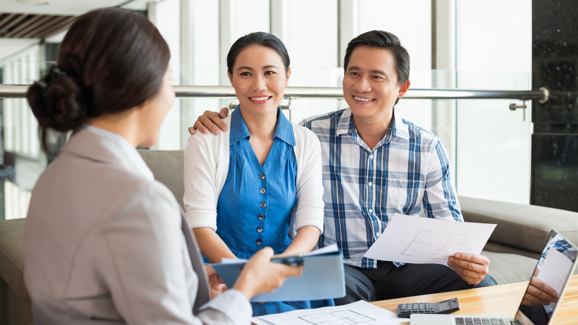 A person is holding a pen in front of a model house.