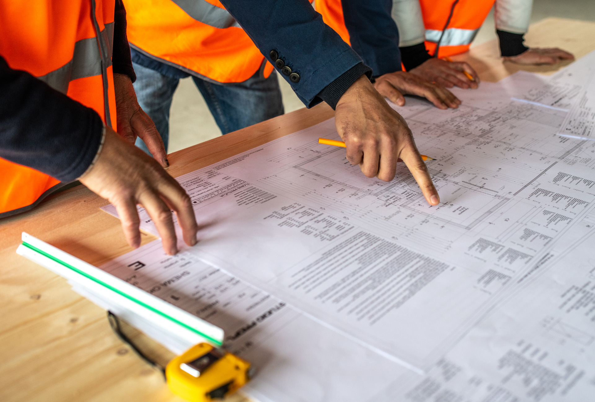 A group of construction workers are looking at a blueprint on a table.