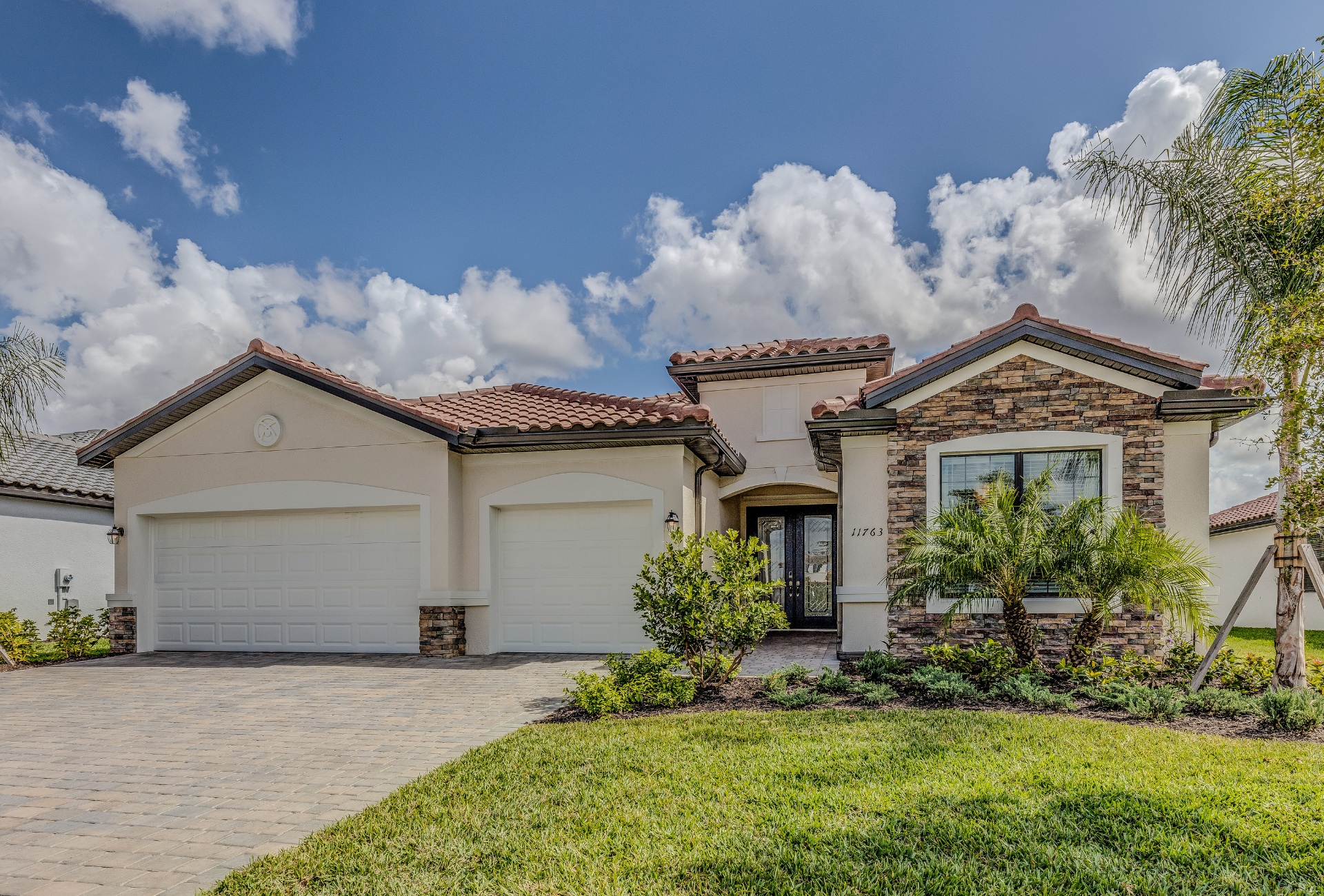 A large white house with a stone roof and a driveway.