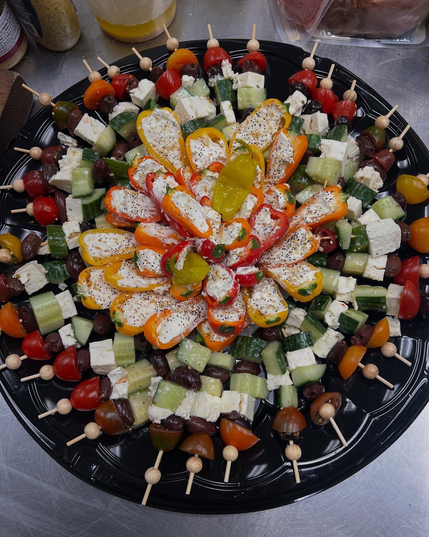 Decorative platter of assorted fruit and cheese cubes arranged in a colorful circular pattern on a black tray