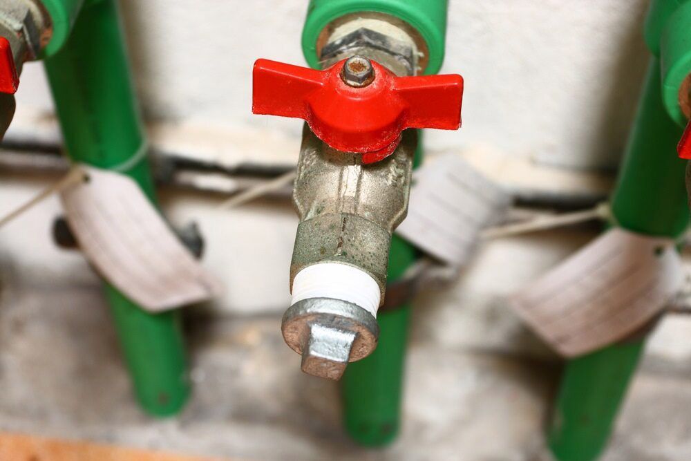 A Close Up of a Faucet With a Red Handle on a Green Pipe — Rock Plumbing & Gasfitting In Cannonvale, QLD