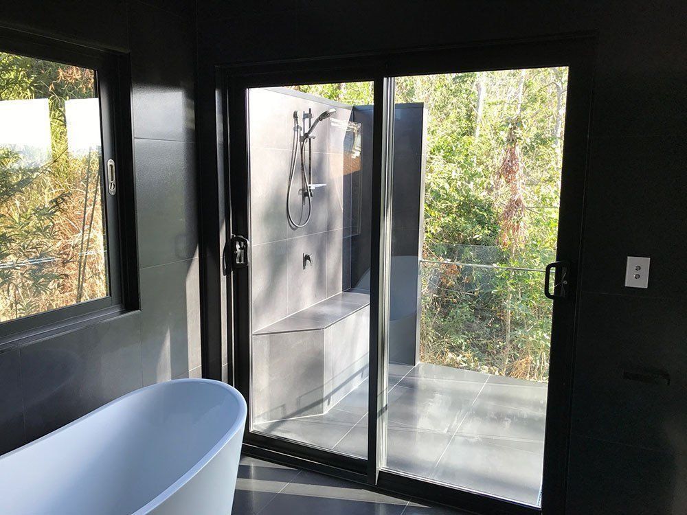A Bathroom With a Bathtub and a Sliding Glass Door — Rock Plumbing & Gasfitting In Cannonvale, QLD