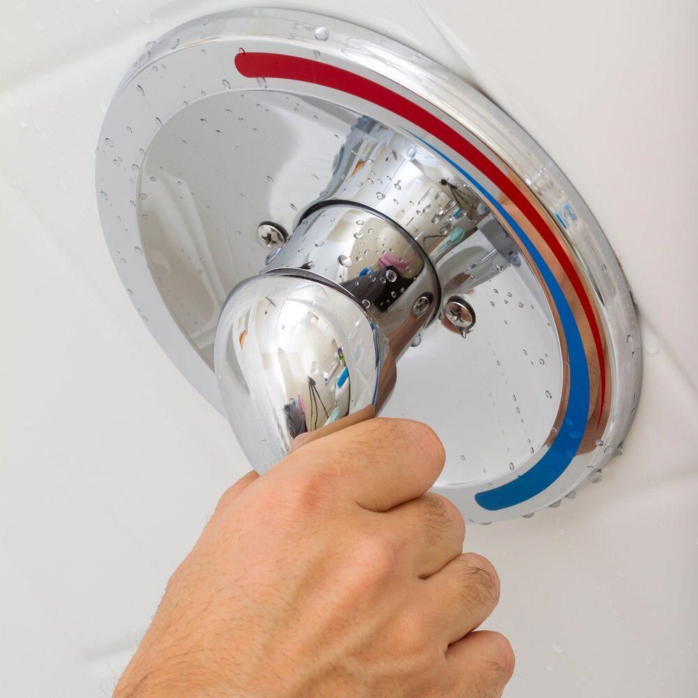 A Person is Holding a Shower Head With a Red and Blue Handle — Rock Plumbing & Gasfitting In Airlie Beach, QLD