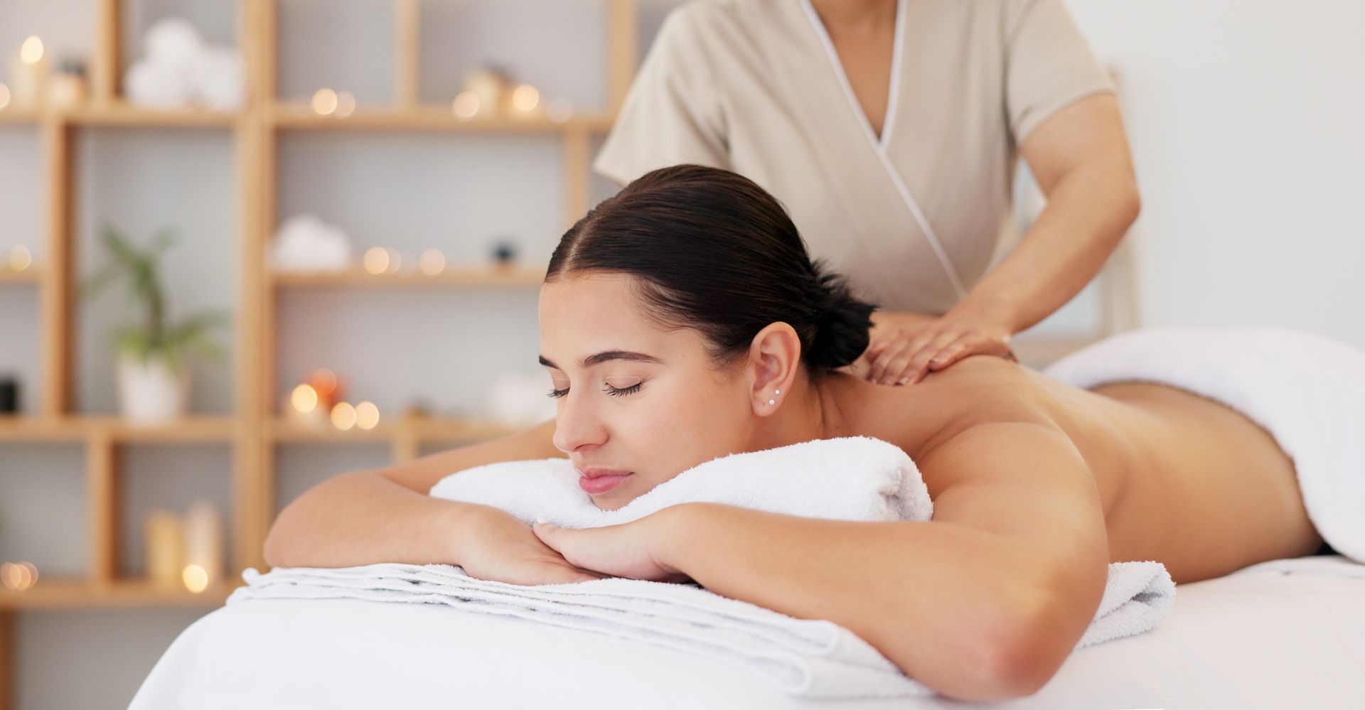 A relaxed woman getting massage therapy from a massage therapist at a spa.