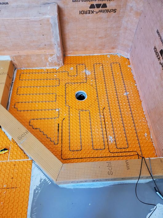 Orange waterproof shower floor with drain and pebble-textured wall surround