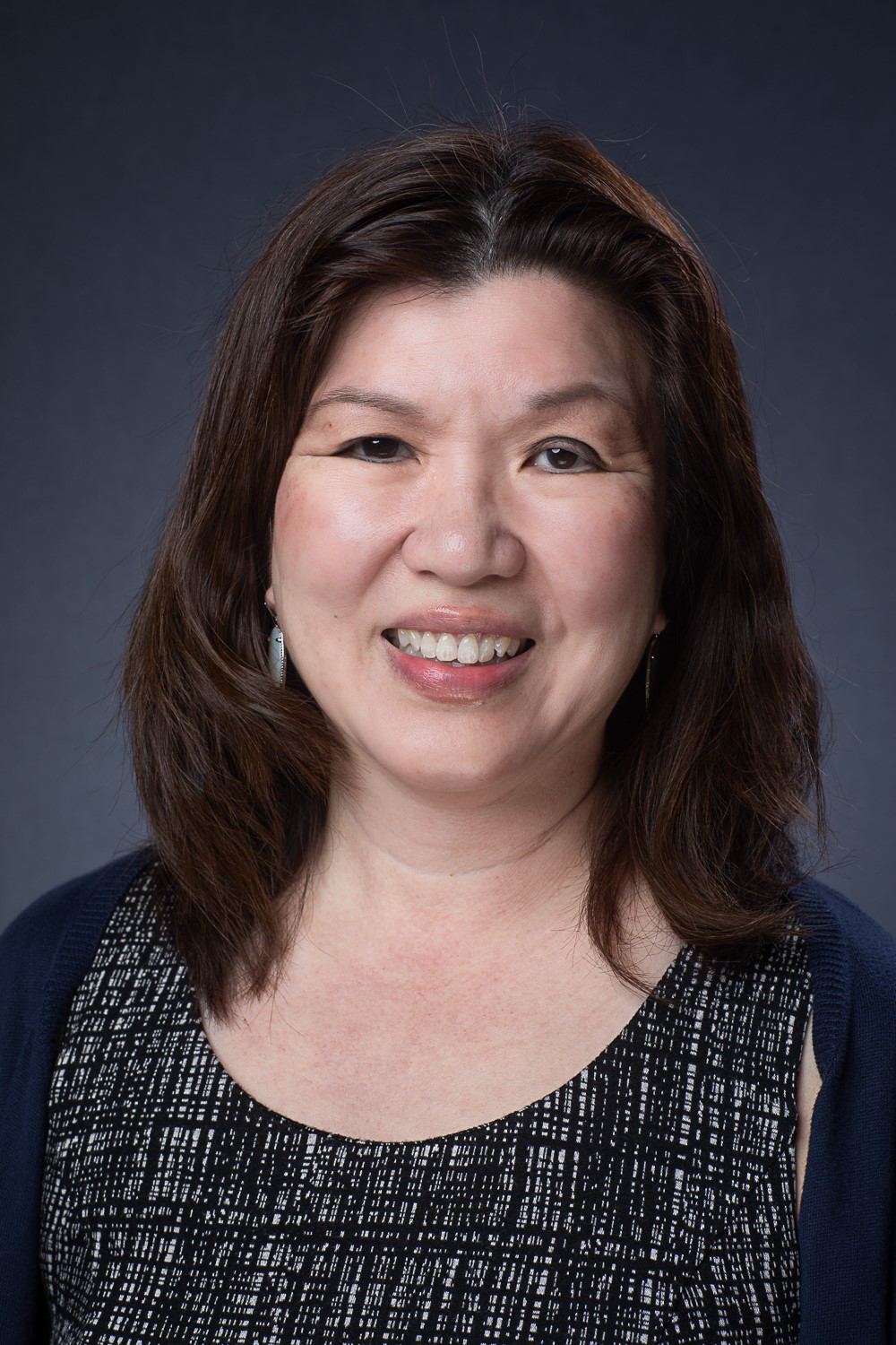 A woman in a black and white dress is smiling for the camera.