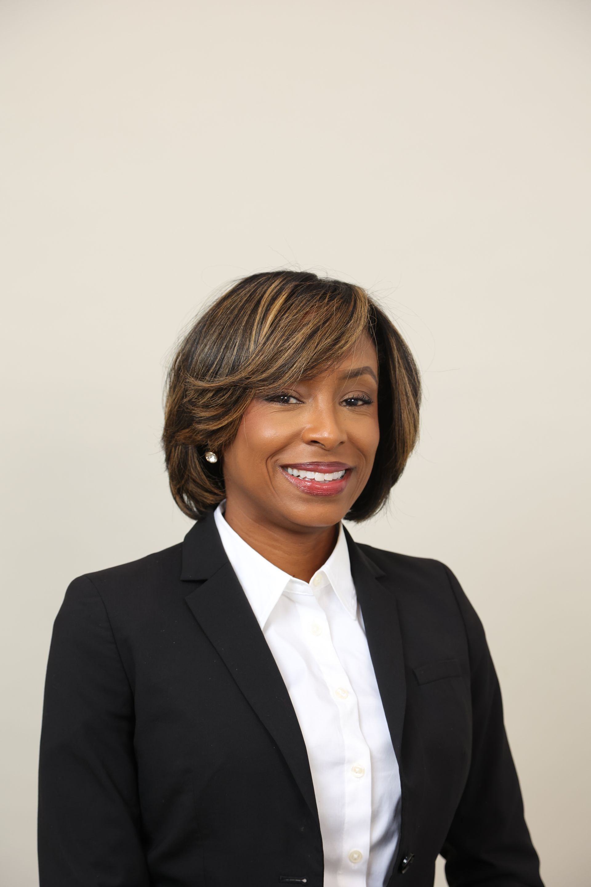 A women with short brown hair is wearing a dark suit and smiling