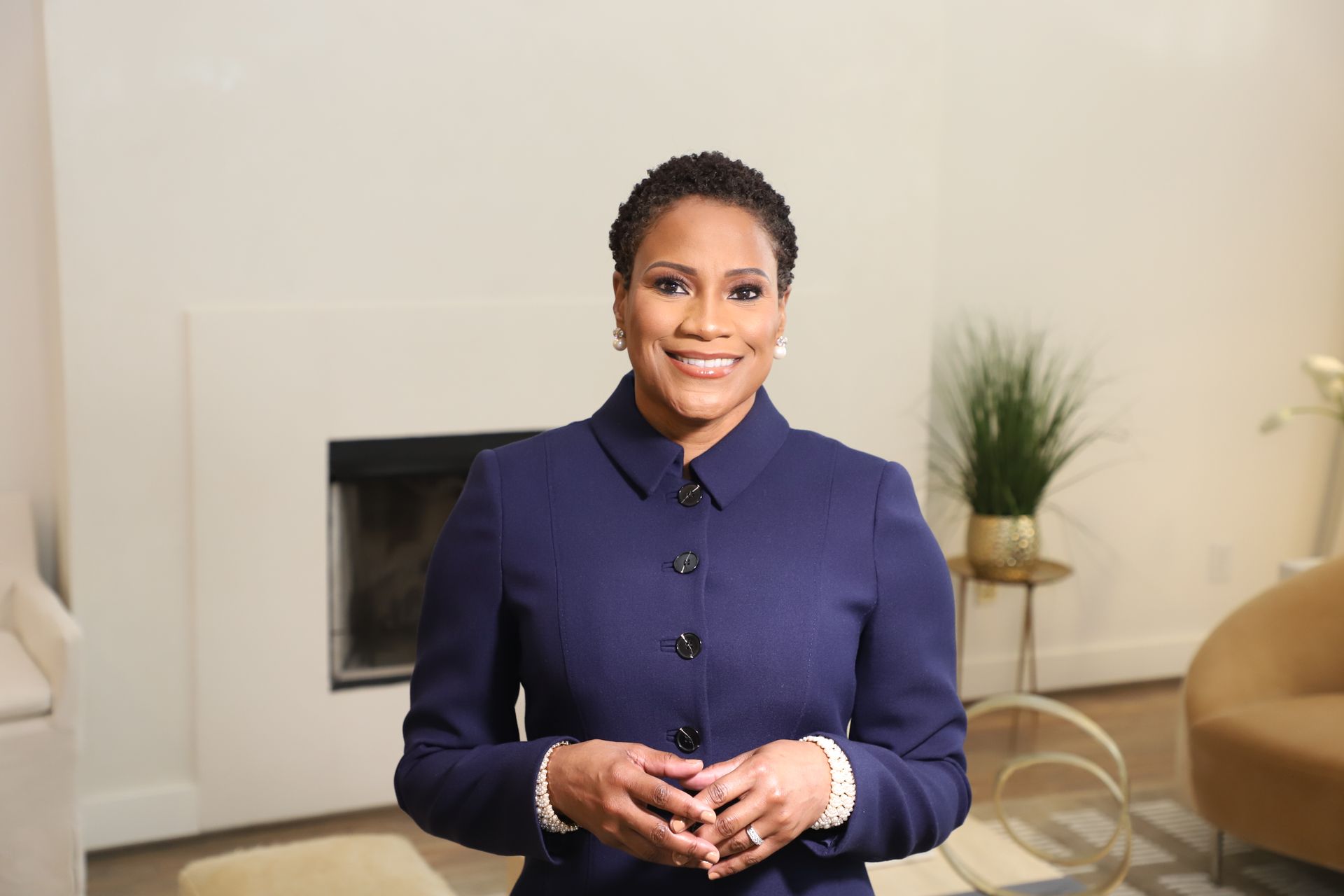 A woman in a blue coat is standing in a living room.