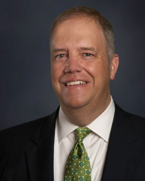 A man in a suit and tie is smiling for the camera