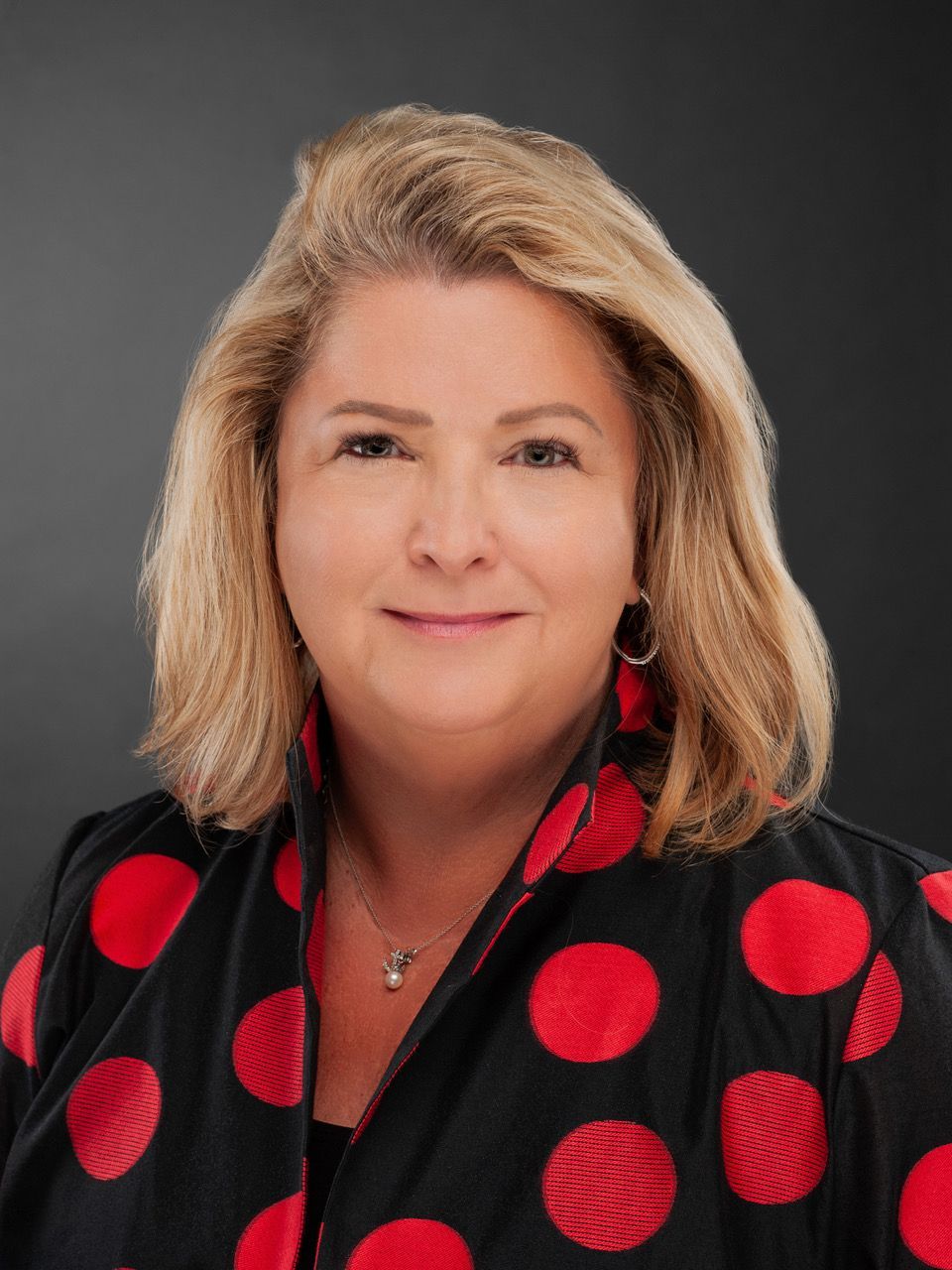 A woman is wearing a red and black polka dot jacket.