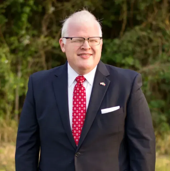 A man in a suit and tie is smiling for the camera