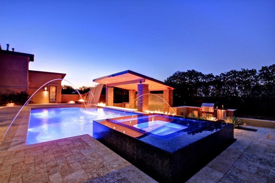 A large swimming pool with a gazebo in the background at night