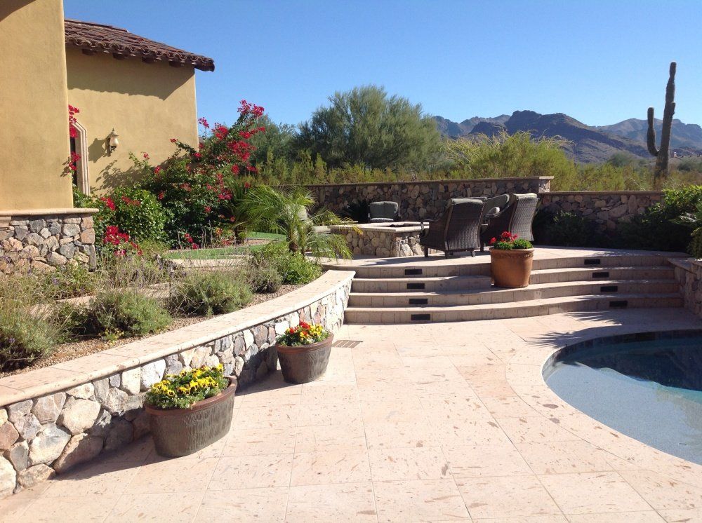 A patio with a swimming pool and a cactus in the background