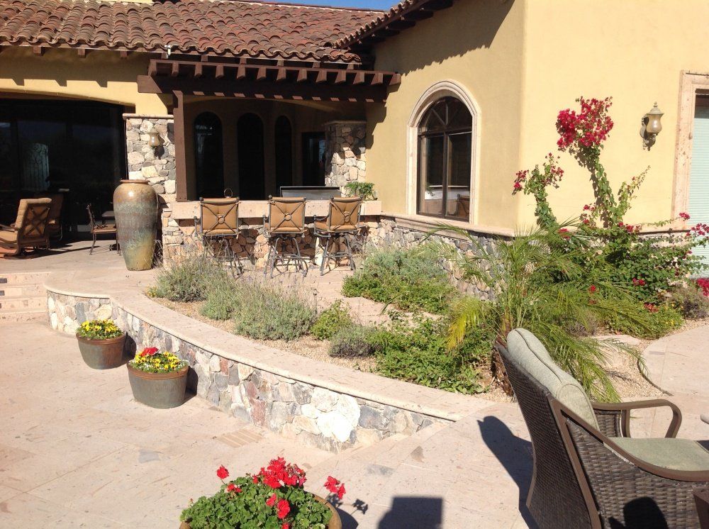 A patio with chairs and potted plants in front of a house