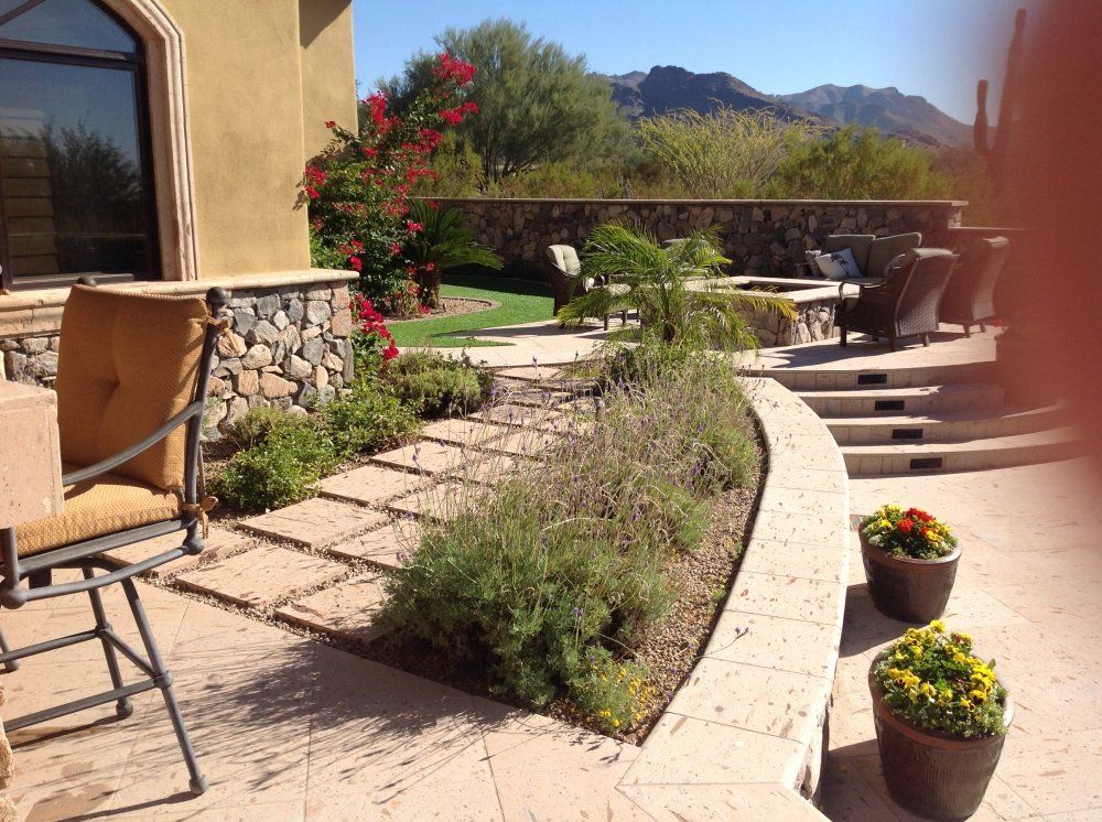 A patio with chairs and potted plants with mountains in the background