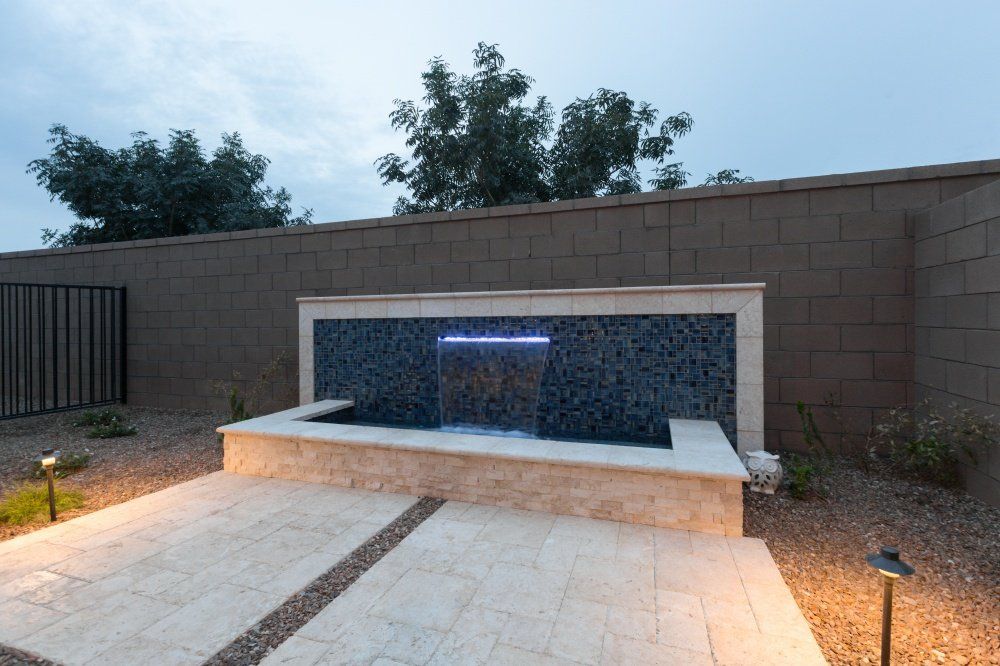 A swimming pool with a waterfall in the backyard of a house.