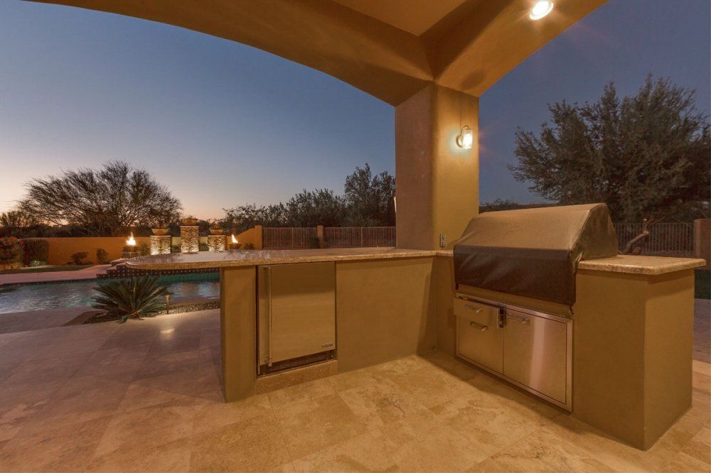 A patio with a grill and a pool at night.