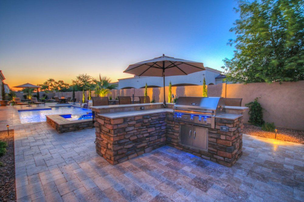 There is a grill and umbrella in the backyard of a house.