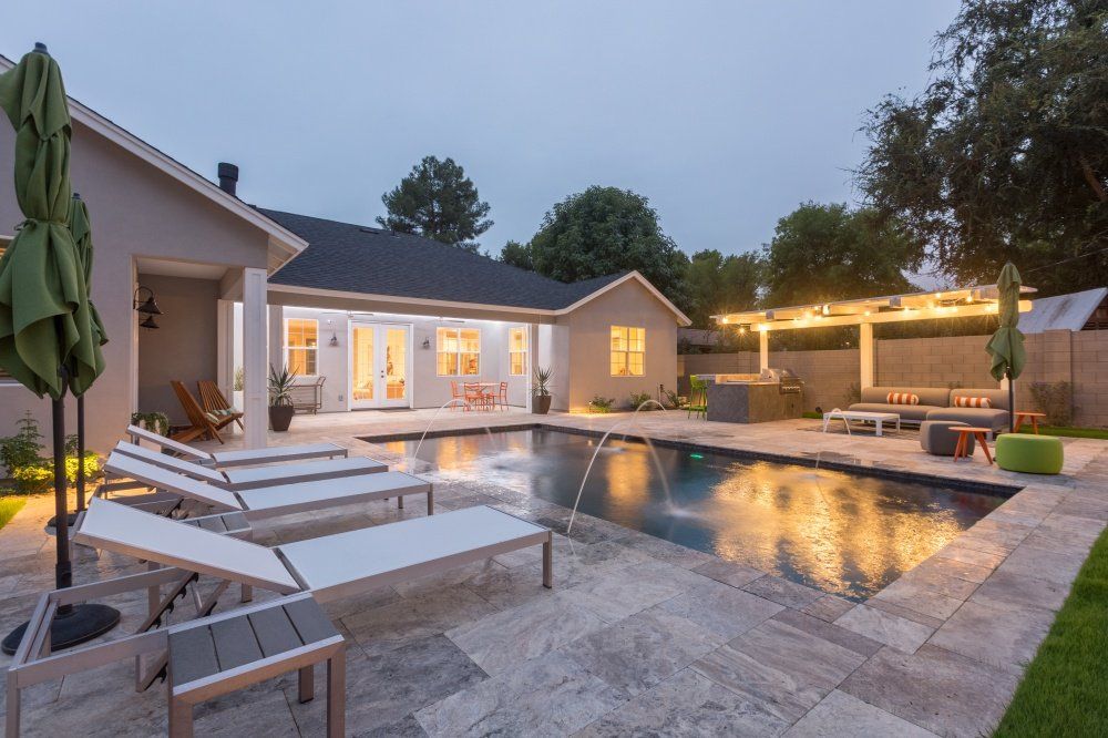 A large swimming pool is in the backyard of a house.