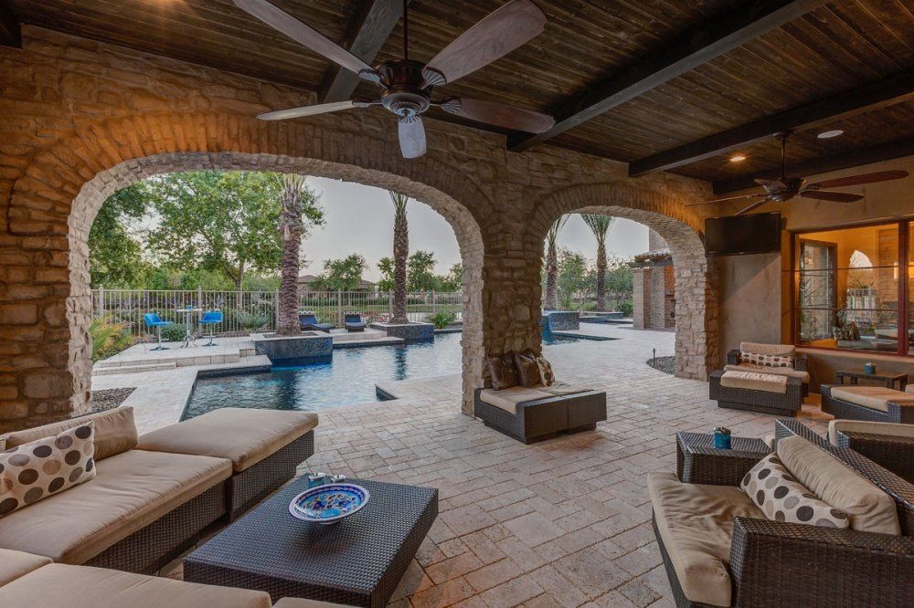 A patio with a lot of furniture and a ceiling fan.