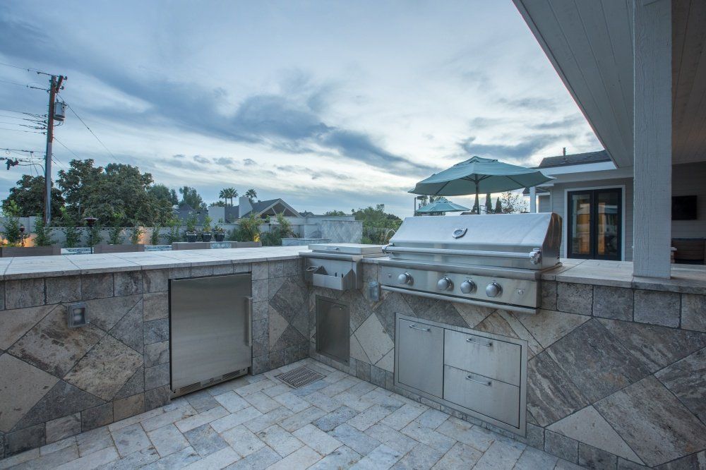 A large outdoor kitchen with a grill and umbrella.