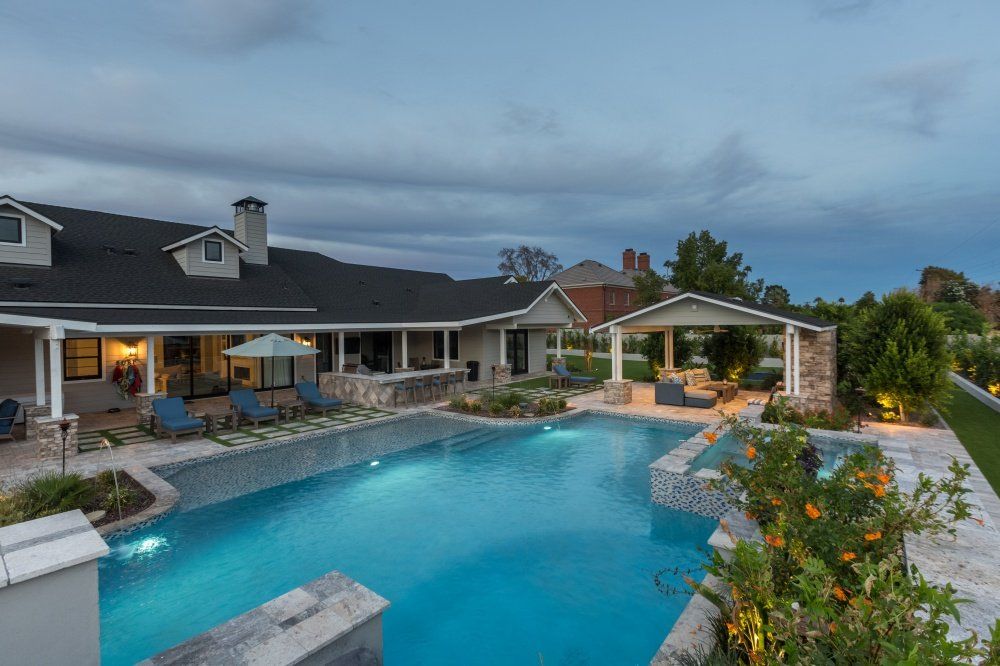 A large swimming pool is in the backyard of a house.