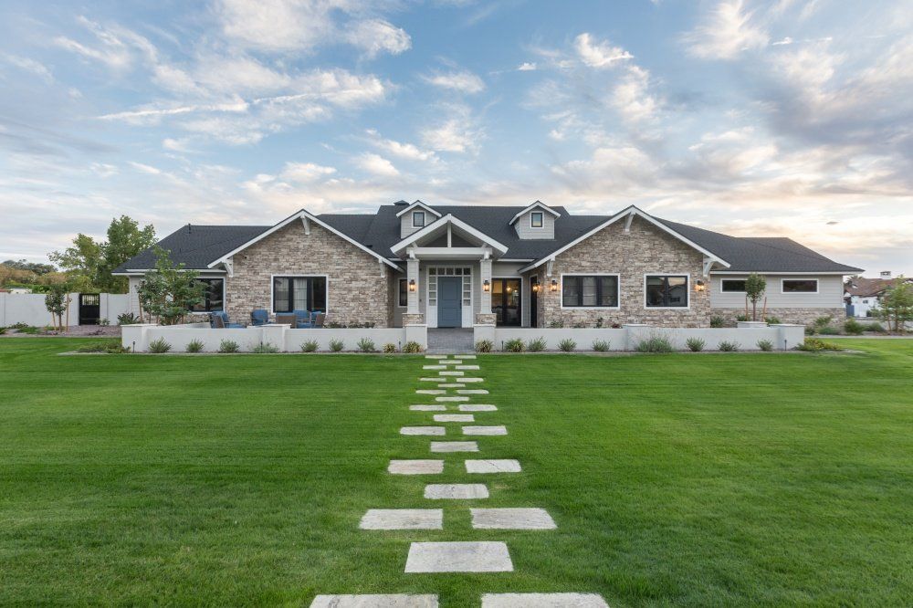 A large house with a lush green lawn and a walkway leading to it.