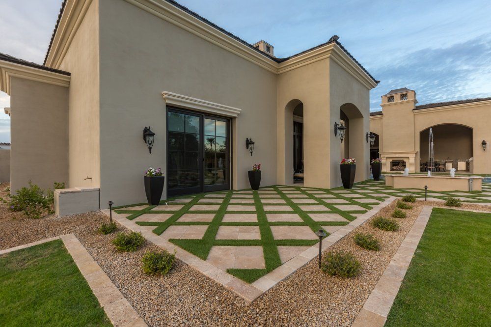 A large house with a patio and lawn in front of it.