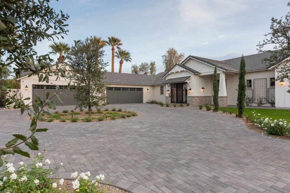 A large house with a brick driveway and two garages