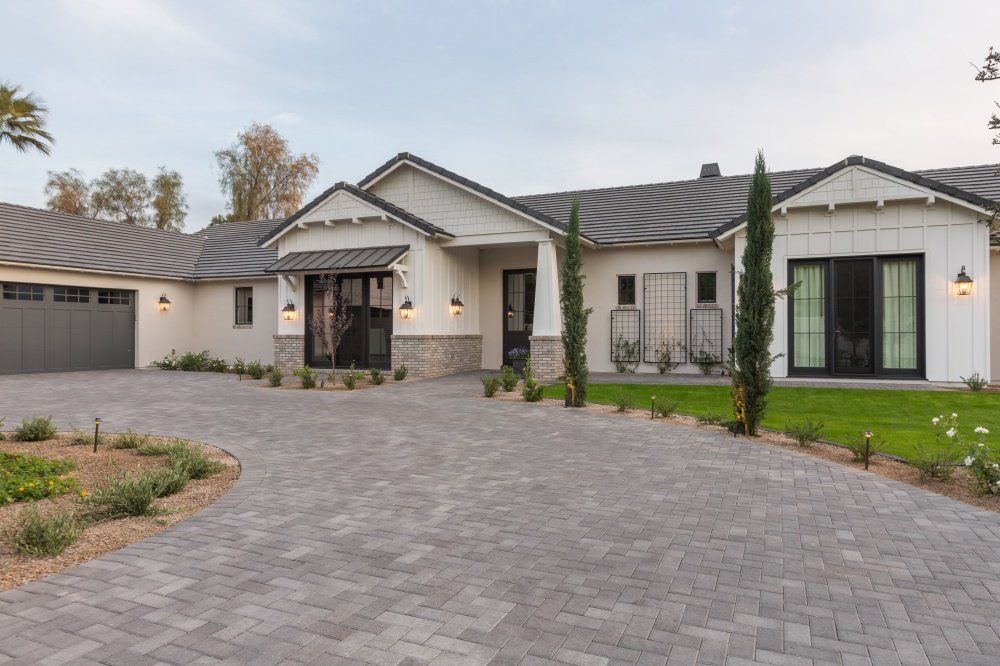 A large white house with a brick driveway and a garage.