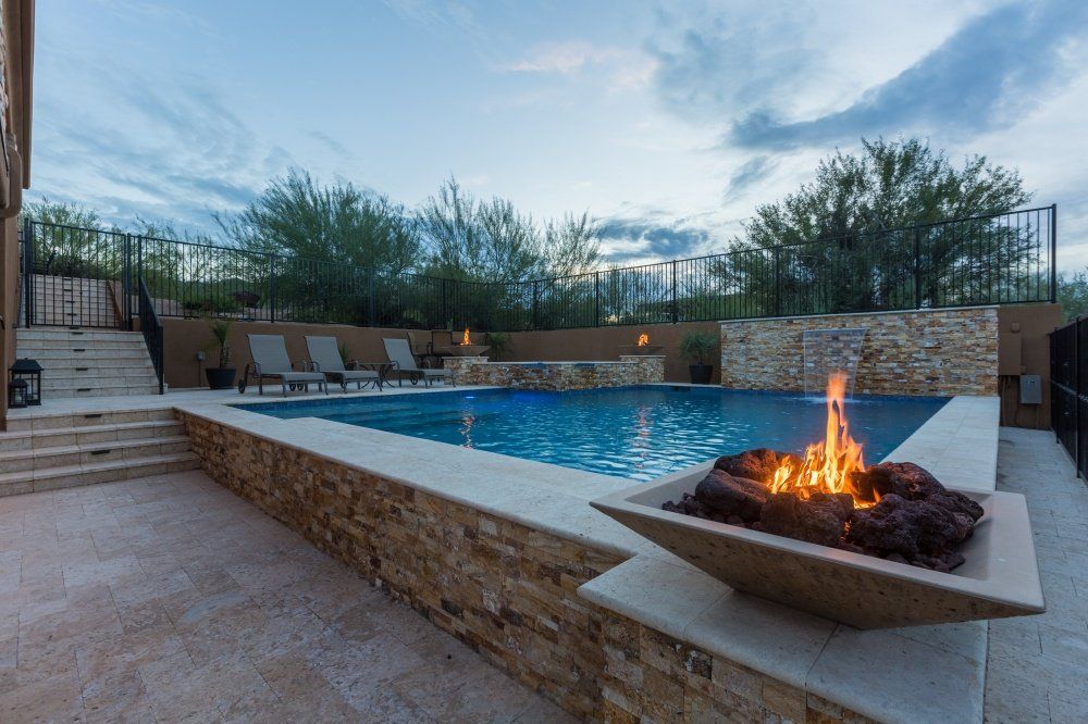 There is a fire pit next to a large swimming pool.
