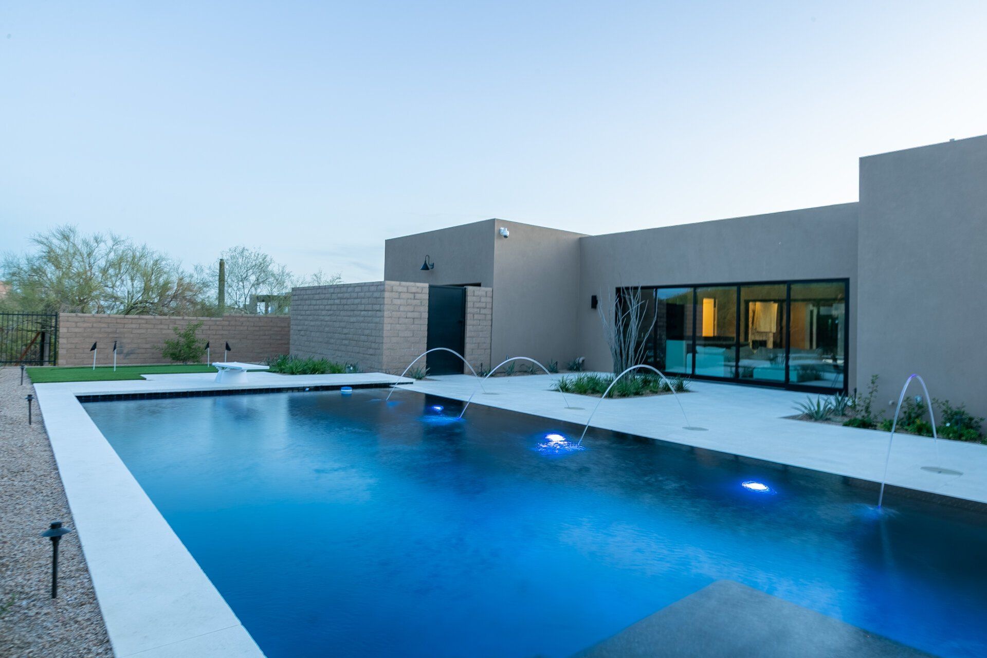 A large swimming pool is in front of a house.