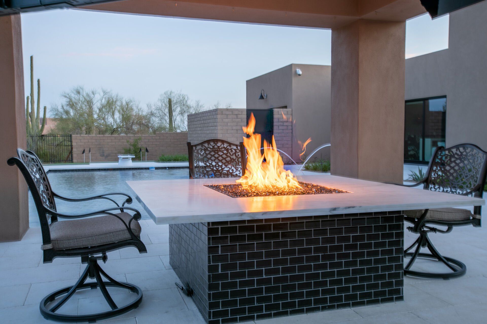 A fire pit is sitting on a patio next to a pool.