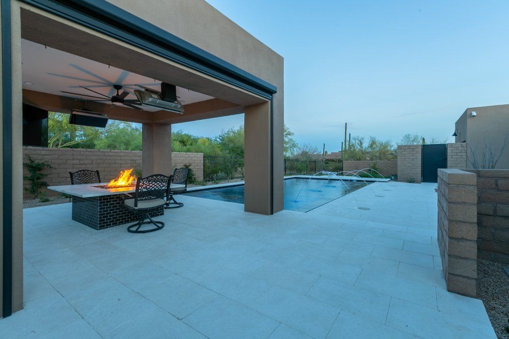 A patio with a table and chairs and a fire pit.
