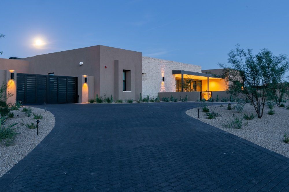 A large house with a driveway leading to it at night.