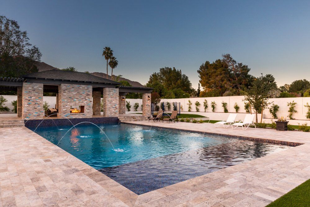 There is a large swimming pool in the backyard of a house.
