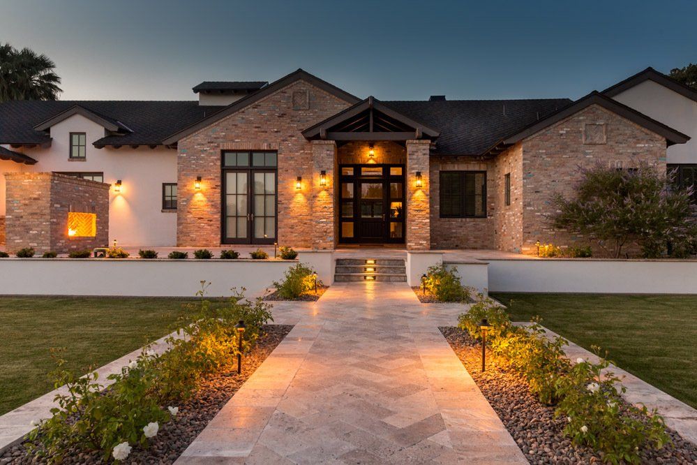 A large brick house with a walkway leading to it is lit up at night.