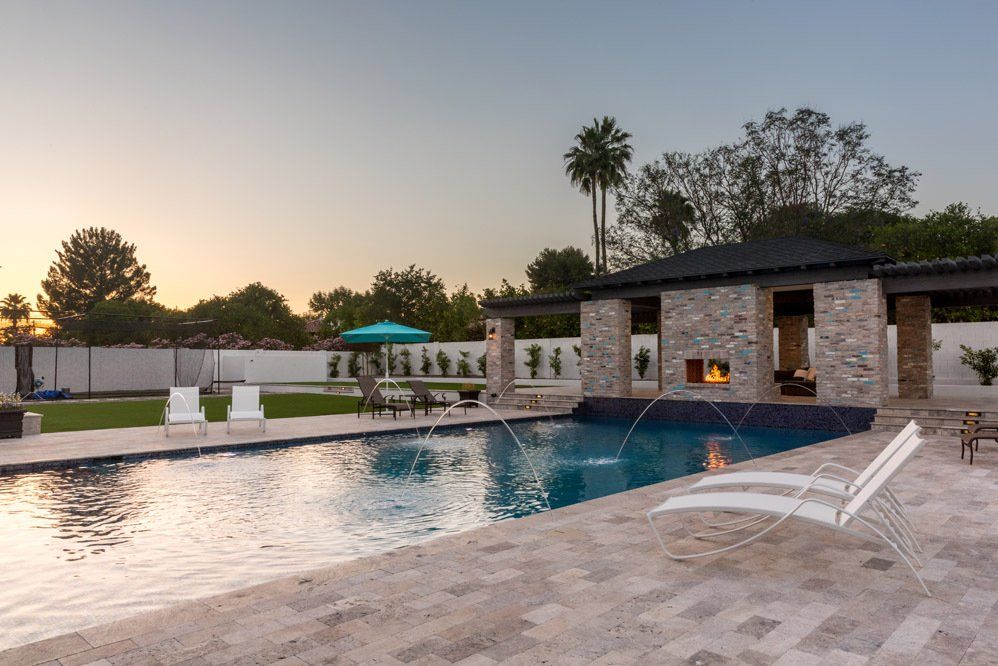 A large swimming pool with a fireplace and chairs around it