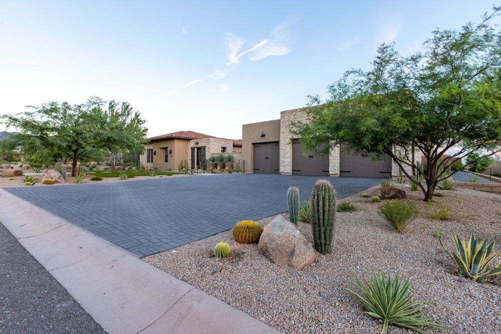 A driveway with cactus and rocks in front of a house.