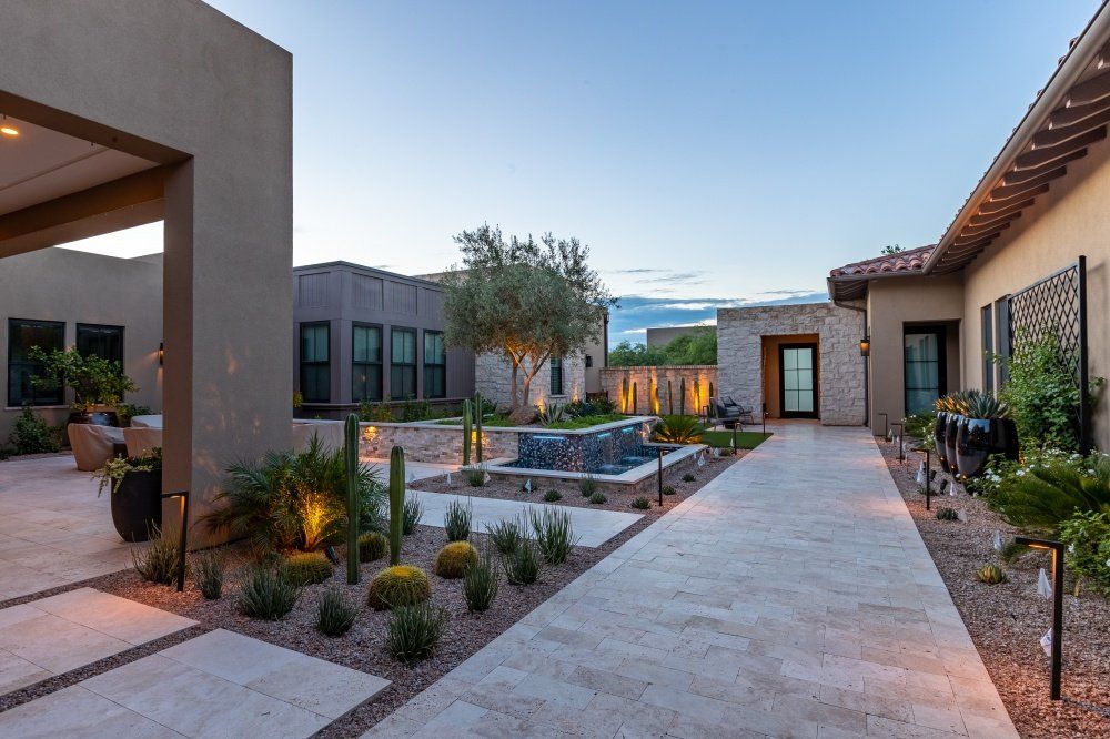 A walkway leading to a large house with a fountain in the middle of it.
