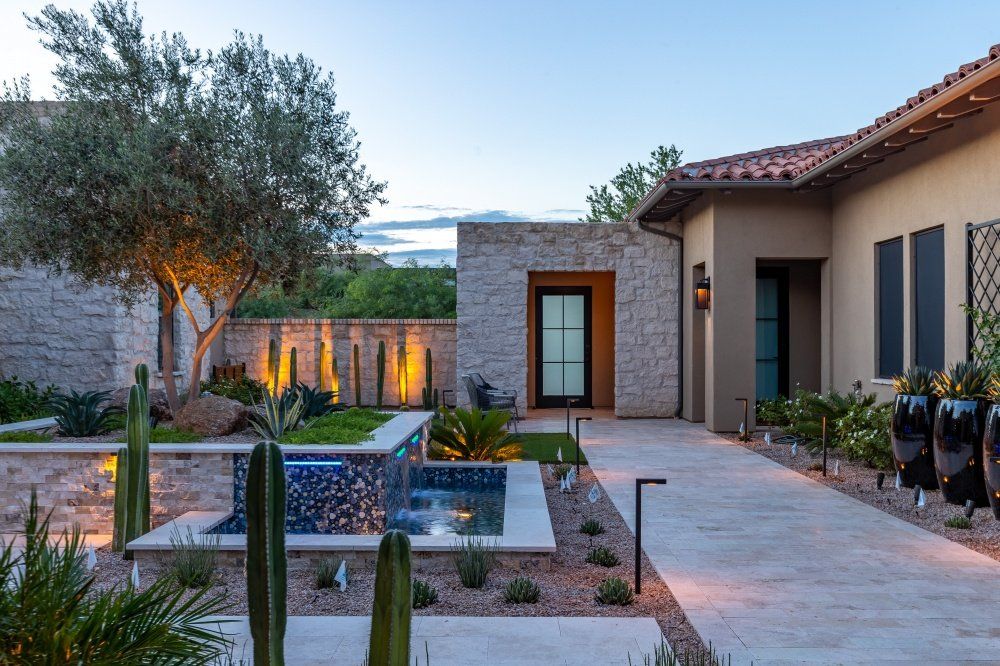 A large house with a pool and cactus in front of it.