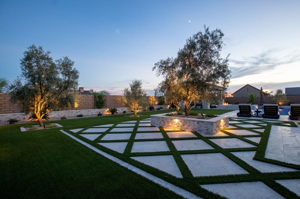 A lush green lawn with trees and a walkway in the middle of it.