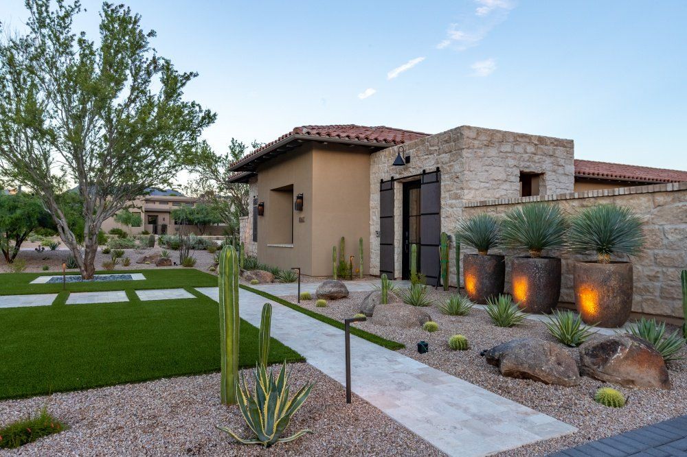 A house with a walkway leading to it and a lot of plants in front of it.