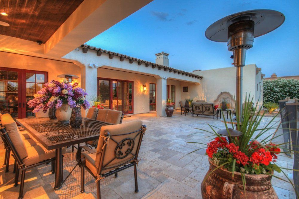 A patio with a table and chairs and a heater.