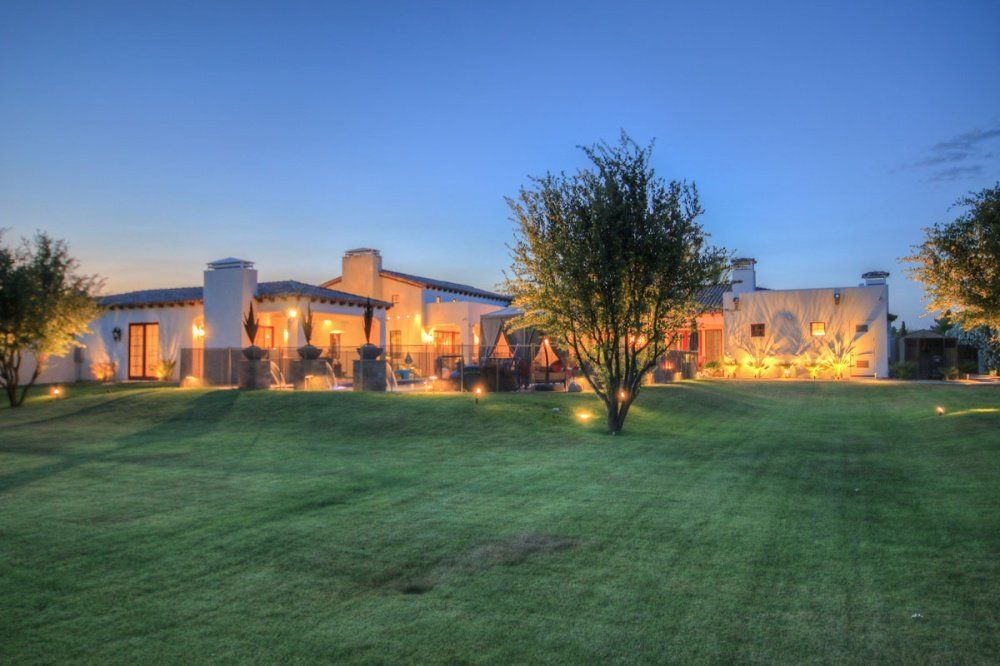 A large white house is sitting on top of a lush green hill.